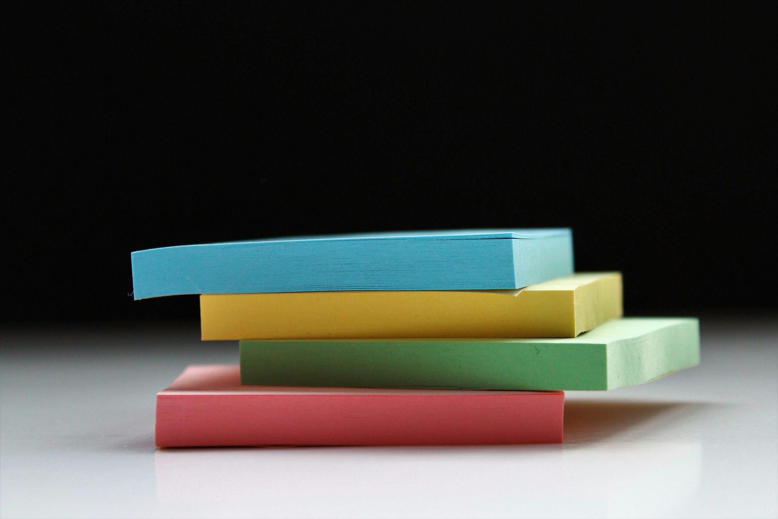 Stack of multi colored post it notes on a half black and white background